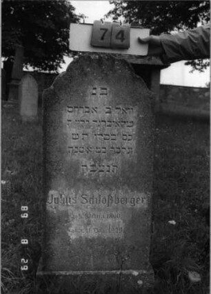 Grabstein 74 (Index: 100108183) Material: Kunststein Zustand: bewachsen Maße HxBxT: 119x50x15 cm Beschreibung: Stele, Abschluß mehrfach konkav gerundet, Sockel: Grabstein 74