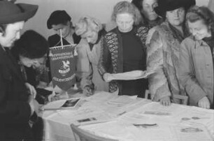 Verabschiedung einer Delegation des Demokratischen Frauenbundes Berlin mit Wilhelmine Schirmer-Pröscher, Elli Schmidt, Roberta Grupa und Eva Schmidt-Kolmer zum Kongress der Internationalen Demokratische Frauenföderation (IDFF) in Moskau : Frauen an einem Tisch mit Informationsmaterial der Internationalen Demokratischen Frauenföderation (IDFF)