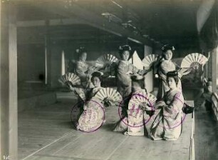 Nagasaki. Sechs junge Geishas in Kimonos präsentieren in Formation ihre Fächer während eines festlichen Empfangs