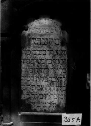 Grabstein 355 (Index: 100111911) Material: Sandstein, weiße Marmorplatte Zustand: leicht verwittert Maße HxBxT: 145x61x30 cm Beschreibung: ädikulaartige Stele mit Säulen, profilierter Sockel, schräg eingezogener Rundbogenabschluß mit Eckakroteren, Schriftplatte Symbolik: segnende Hände, Ranken, Rundbogenfries: Grabstein 355A