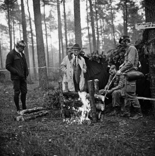 Munster: Truppenübungsplatz Munster-Nord: Gefechtsübung der Panzerbrigade 17: Wald: Stadtverordneter Dieter Achterberg und Bürgerworthalter Georg Koch an Balkenfeuer: rechts zwei Soldaten vor Unterstand: 05.11.1975