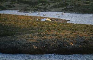 Spanien. Menorca. Cap Cavalleria. Felszunge und kleines weisses Haus im Abendlicht