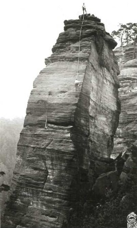 Böhmische Schweiz, Elbtal - Rechtes Ufer (Labské údolí - Pravý břeh). Wotanskegel (Vojtěch). Südwestwand mit zum Gipfel nachholender Seilschaft Klemm