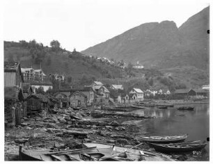 Merok. Strand mit Ruderbooten. Blick über Holzhütten, Hotel Geiranger und Hotel Merok