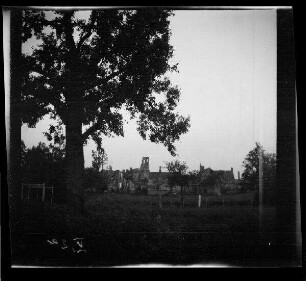 Messines (=Mesen, Belgien): Ortsansicht mit Gebäudenruinen, im Vordergrund ein Feld (Distanzaufnahme) ("Blick auf Messines")