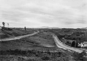 Landschaftsblick : Blick in eine hügelige Landschaft. Rechts und Links eine unbefestigte Straße und vereinzelte Häuser.