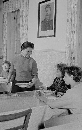 Junge Mädchen beim gemeinsamen Essen, vermutlich Speisesaal eines Wohnheimes, an der Wand ein Porträts Stalins