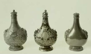 Deckelflaschen in Pilgerflaschenform: links mit plastisch aufgelegtem Schmuck und eingeschliffener Ornamentik in der Art von Glasschliffarbeiten, Oberfläche rauh & Mitte: Ornamentik durch die schwarze Glasur in die rote Steinzeugmasse hineingeschliffen & rechts: Oberfläche glatt geschliffen