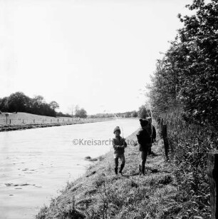 Trave: Kinder auf Trave-Wanderweg mit Schilfbinsen in der Hand: rechts daneben Büsche: hinten links Weide und Knick