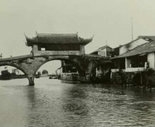 China. Alte Straßenbrücke über Fluß oder Kanal in einem Landstädtchen bei Suzhou, nahe der Jangtse-Mündung, am Ufer Wohnhäuser