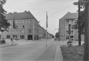 Unbekannter Ort. Blick auf eine Straßenkreuzung mit Wohn- und Geschäftshäusern (HO-Laden, Sibylle-Friseurhandwerk)