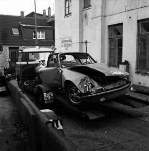 Königstraße: Hof des Abschleppunternehmens von Herbert Abraham: nach Verkehrsunfall: Wrack von Unfall-Pkw Porsche auf Plattform von Abschleppwagen: links Plattform von zweitem Abschleppwagen: rechts Haus, an Fassade Aufschrift "Autovermietung an Selbstfahrer": hinten Straße, Wohnhaus