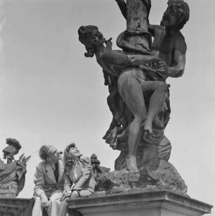 Elisabeth Gremmler sitzt zusammen mit einem befreundeten Mann auf einem Geländer neben einer Statue