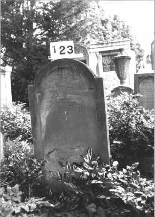 Grabstein 123 (Index: 100114293) Material: Sandstein Zustand: stark abgeblättert mit großem Textverlust Maße HxBxT: 88x50x10 cm Beschreibung: Stele, eingezogener Rundbogen Besonderheit: Kindergrab: Grabstein 123