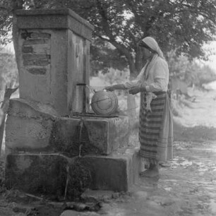 Roma-Mädchen mit Wasserflasche am Brunnen in Karlowo im Rosental