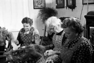 Frauen beim Flachsspinnen in Wohnstube