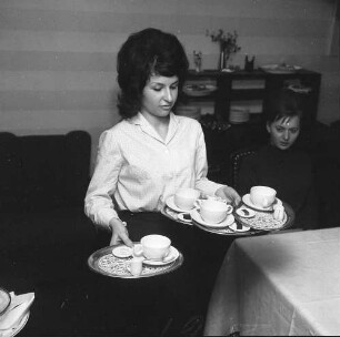 Servierfachschule. Angehende Kellnerin erlernt das Tragen von vier kleinen Tabletts mit Kaffeetassen