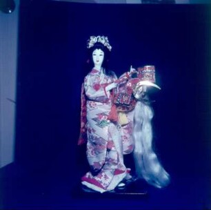 Japan. Japanische Yaegaki-Puppe im bestickten Seidenkleid, ein Haarteil in der Hand haltend