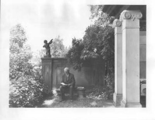 Villengarten. Alter Mann beim Lesen vor einem Mauervorsprung mit musizierendem Putto