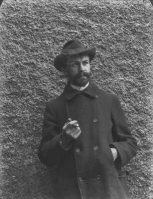 Portrait Rudolf Zimmermann : Portrait von Rudolf Zimmermann mit Zigarre in der Hand vor einer Hauswand.
