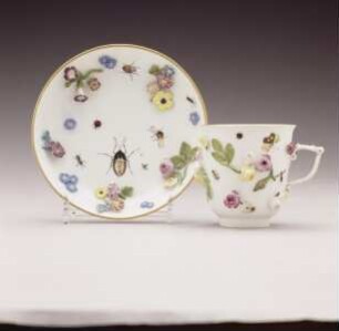 Tasse und Unterschale mit plastischen Blüten und Insekten