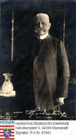 Hindenburg, Paul v. (1847-1934) / Porträt, neben Tisch mit Kristallvase stehend, Kniestück, mit faksimilierter Unterschrift
