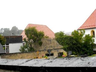 Ansicht von Südwesten mit Kirchhofmauer (Steinbrüstung des Wehrgangs erhalten) über ehemaligem Grabenvorfeld