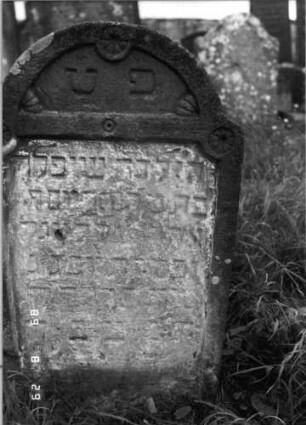 Grabstein 157 (Index: 100107426) Material: heller Sandstein Zustand: stark verwittert, teilweise Textverlust Maße HxBxT: 77x40x10 cm Beschreibung: Stele mit schwach eingezogenem Rundbogenabschluß, Schriftfeld eingetieft Symbolik: Rosetten Besonderheit: Kindergrab: Grabstein 157A