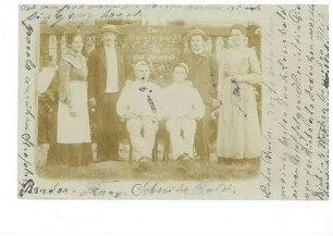 Zwei Frauen und vier Männer vor einem Schild "Zur Erinnerung Hotel Post Saison 1903 Bad Herrenalb"
