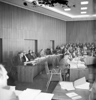 Kreistagssitzungssaal: Kreistagssitzung: Blick vom Podium auf links sitzende Kreistagsabgeordnete: im Vordergrund Tische auf Podium
