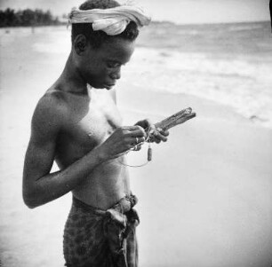 Junge mit Fischköder : Ein Junge mit Köder und Angelleine am Strand.