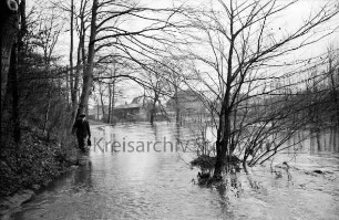 Beste: Kurpark: Hochwasser: Blick von Fußgängerbrücke: vorn Mitte Büsche im Wasser: links Böschung mit Bäumen: hinten Mitte hinter Büschen und Bäumen Gebäude auf Gelände der Papierfabrik und Am Kurpark