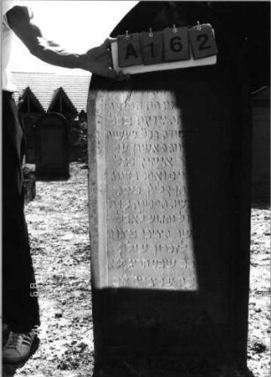 Grabstein 162 (Index: 99798012) Material: Sandstein, rot Zustand: leicht verwittert Maße HxBxT: 142x60x17 cm Beschreibung: Stele, Spitzbogenabschluß Symbolik: Maßwerk: Grabstein 162A