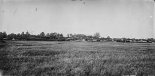 Siedlung : Blick über eine Wiese auf eine Ortschaft.