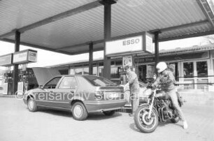 Sandesneben (Kreis Herzogtum Lauenburg): Tankstelle Esso-Station Osterhoff: Hauptstraße, bei Abzweig Blumenstraße: an Zapfsäulen: Serviceleiter Thomas Elsler bei Pkw im Gespräch mit Motorradfahrer: 14. April 1989