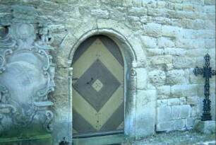 Romanisches Portal Kirchennordseite, links davon barocker Grabstein