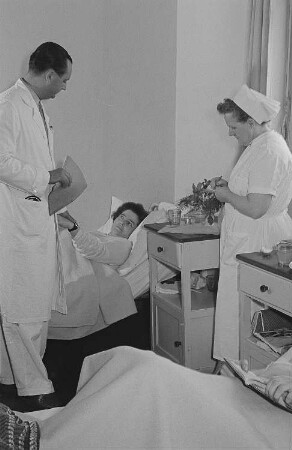 Ein Arzt, eine Krankenschwester sowie eine Patientin bei der Visite in der Betriebspoliklinik der Transmasch Leipzig