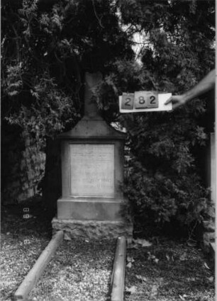 Grabstein 282 (Index: 99797062) Material: Sandstein, weiße Marmorplatte Zustand: Säule z. T. weggebrochen/sonst gut Maße HxBxT: 137x52x21 cm Beschreibung: postamentierte abgebrochene Säule, rechteckige Schriftplatte: Grabstein 282