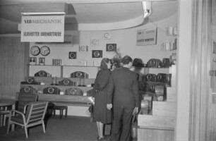 Besucher an einem Messestand mit Uhren des VEB Mechanik Glashütter Uhrenbetriebe