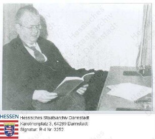 Werner, Ferdinand Prof. Dr. phil. (1876-1961) / Porträt, an Schreibtisch im Arbeitszimmer des Landtagspräsidenten sitzend, in einem Buch lesend, Kniestück