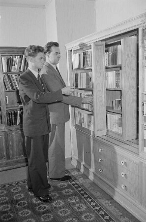 Zwei Männer begutachten einen auf der Leipziger Herbstmesse 1955 ausgestellten Bücherschrank