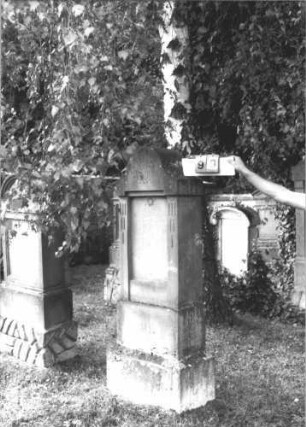 Grabstein 99 (Index: 99609735) Material: Sandstein Zustand: leicht verwittert, Inschriftplatte fehlt Maße HxBxT: 173x62x27 cm Beschreibung: Stele, geschwungener Bogenabschluß, rechteckige eingelassene Schriftplatte fehlt, getreppter Sockel Symbolik: floral Besonderheit: IV 341: Grabstein 99