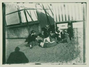 Jungen und Mädchen vor den Rummelbuden auf dem Boden hockend
