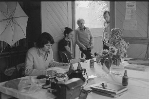 Höfgen. Akt-Pleinair 1979. Die Fotografen Eva Mahn, Günter Rössler und andere Teilnehmer im Gespräch, am Tisch sitzend ein Fotomodell mit Turban