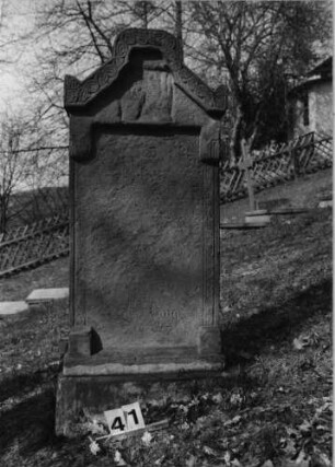 Grabstein 41 (Index: 100080806) Material: Sandstein Zustand: völlig verwittert, nur einzelne Buchstaben erkennbar Maße HxBxT: 126x52x21 cm Beschreibung: Stele, Sockel, giebelartiger Abschluß rechteckig erhöht mit Eckakroteren Symbolik: verwitterte segnende Hände, Blätterfries: Grabstein 41