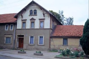 Wohnhaus eines Beamten des ehemaligen Gutes; Giebelschmuck; davor Freifläche mit Blumenrabatten