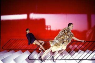 Models auf einer Treppe mit Geländer vor rotem Hintergrund, Werbeaufnahme für Müssig AG