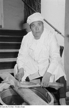 Ein chinesischer Koch beim bearbeiten von Lebensmitteln