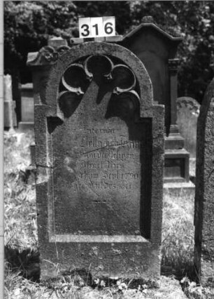 Grabstein 316 (Index: 100085220) Zustand: Stein zerschlag. /zusammengefügt Maße HxBxT: 119x60x13 cm Beschreibung: Stele, eingezogener Rundbogenabschluß, Schriftfeld eingetieft mit Maßwerk: Grabstein 316