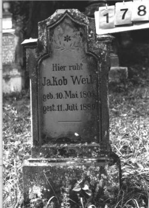 Grabstein 178 (Index: 100106303) Material: Sandstein Zustand: leicht verwittert, Mittelaufsatz fehlt Maße HxBxT: 108x51x16 cm Beschreibung: Stele, Abschluß Sonderform, Verdachung, Mittelaufsatz fehlt, Sockel, Schriftfeld eingetieft Symbolik: Zweige, Stern: Grabstein 178